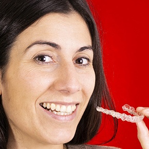 Woman with Invisalign in Manchester smiling on a red background