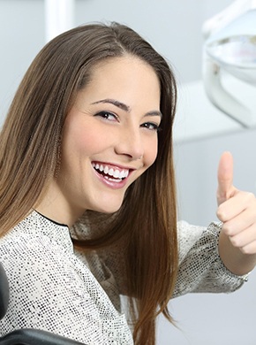 young attractive woman in dentist chair happy giving thumb up